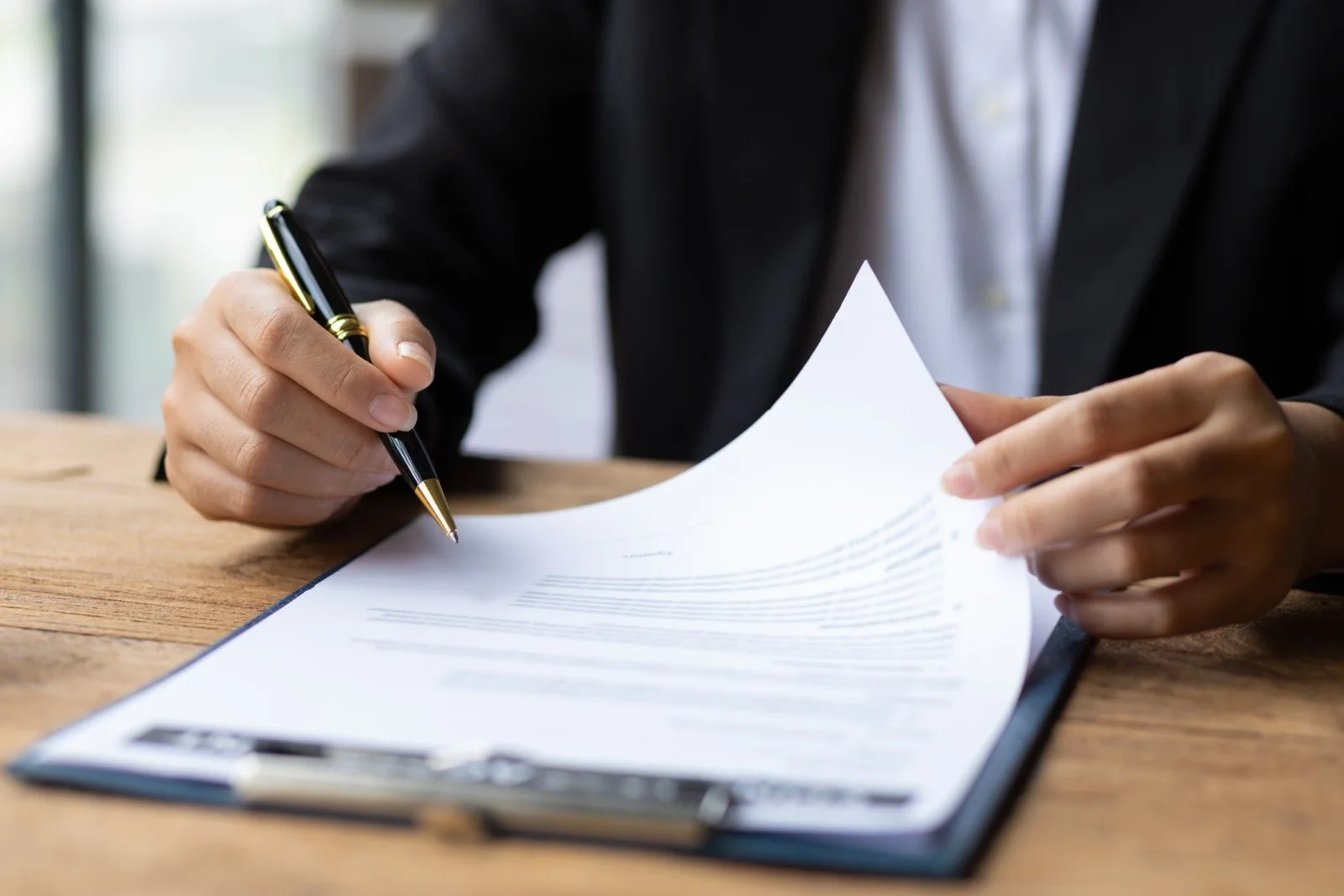 Een persoon controleert met een pen een document op een klembord